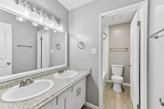 A bathroom with a toilet, sink, and mirror.