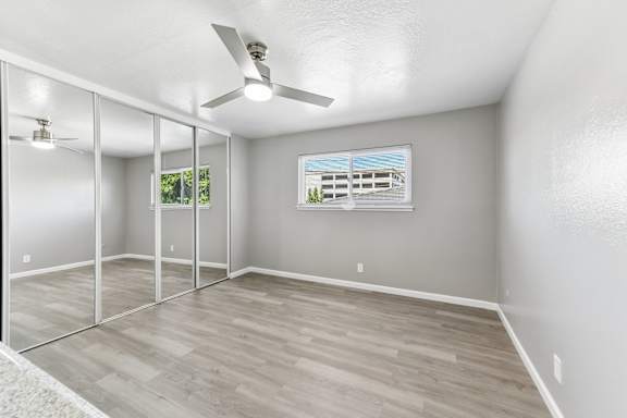 A room with a ceiling fan and a window showing a building outside.