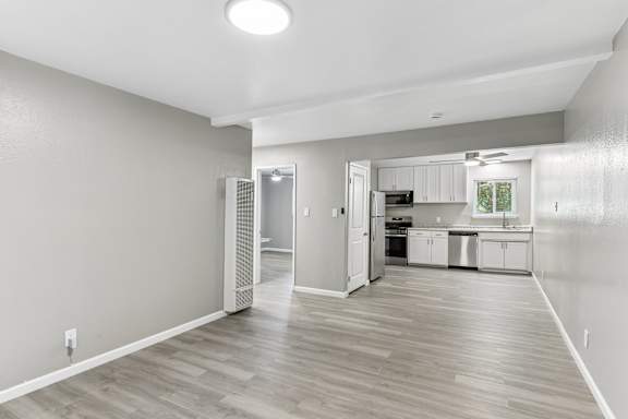 A spacious kitchen and living room with wood flooring and white walls.