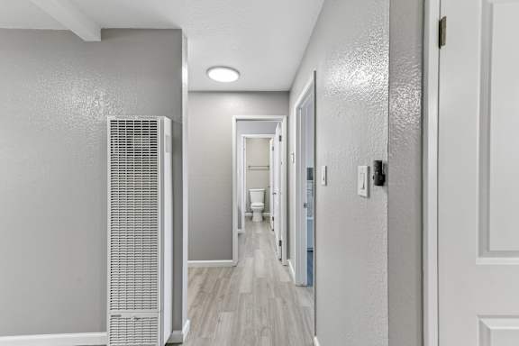 A long hallway with doors on both sides and a wall-mounted air conditioner on the left.