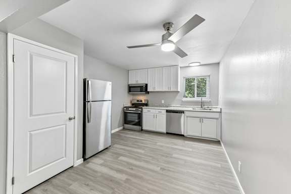 A kitchen with white cabinets and a refrigerator.