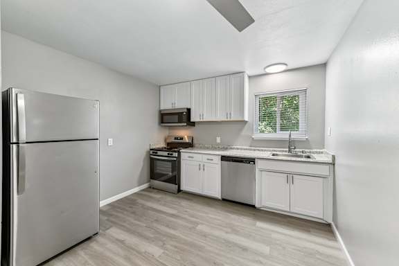 A kitchen with a refrigerator, oven, and sink.