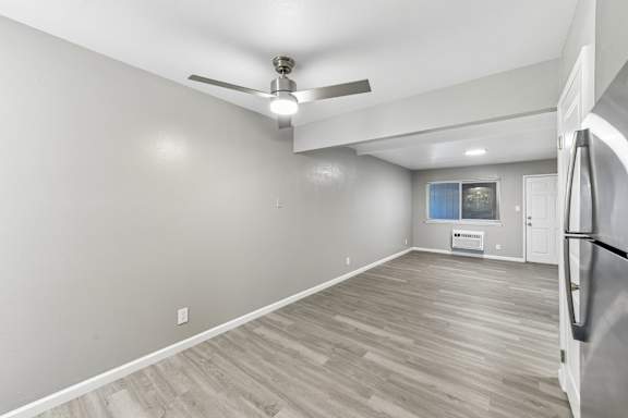 Livingroom/Dining area with a ceiling fan and vinyl plank flooring, and a window with blinds next to the front door. Wall AC unit below the window.