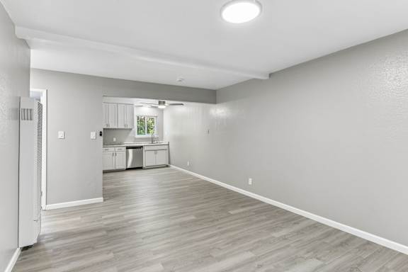 A spacious living room with vinyl plank flooring and a kitchen in the background.