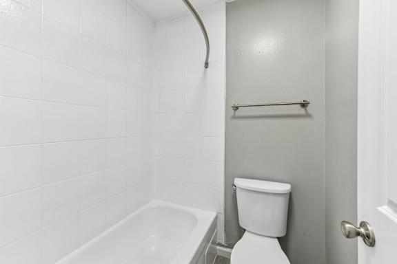 A white toilet sits next to a white bathtub in a bathroom.