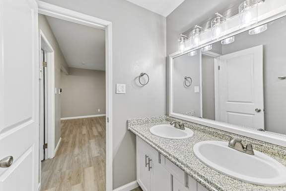 A bathroom with a white sink and mirror.