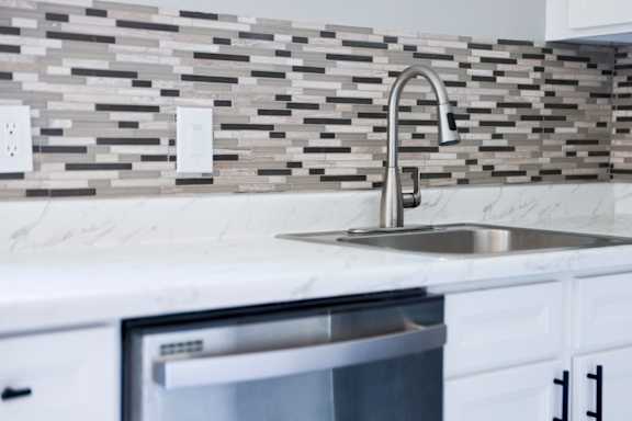 Floor Plan  A modern kitchen with a marble looking countertop and a stainless steel sink.