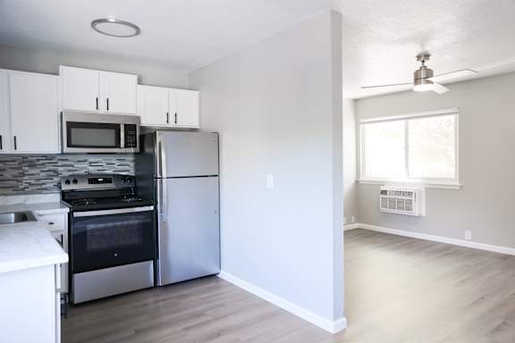 A kitchen with a stainless steel stove top oven, microwave, and refrigerator.