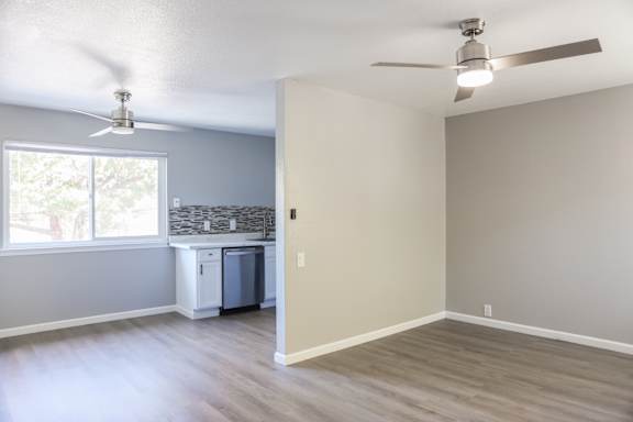 A room with a ceiling fan and a window overlooking a kitchen.
