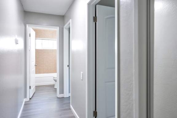 A hallway with a white door and a window.