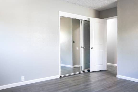 A room with a white door and a mirror on the wall.