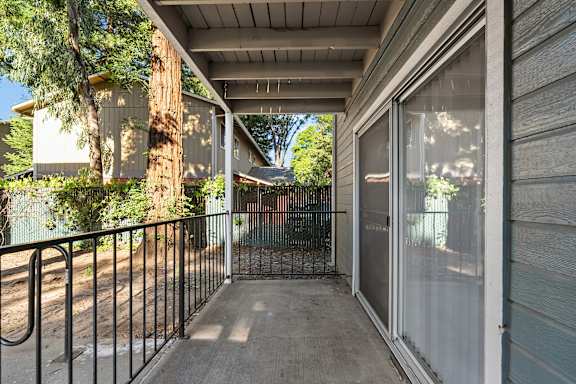 Covered patio with sliding glass door and railing at Redwood Cove Apartments, Chico, California