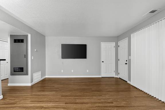 Living room with wall mounted tv and vertical blinds at Redwood Cove Apartments, California