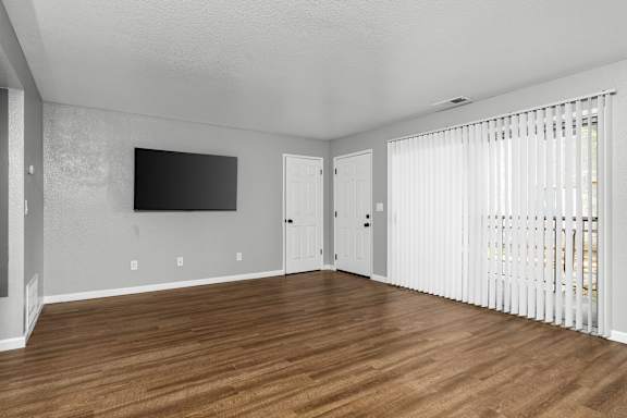Living room with mounted tv and patio blinds at Redwood Cove Apartments, Chico, CA 95928