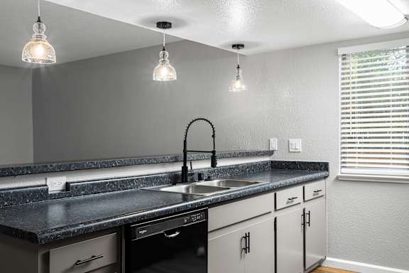 Kitchen with black appliances and pendant lights at Redwood Cove Apartments, California, 95928