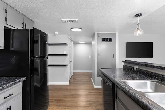 Kitchen and living area with black appliances at Redwood Cove Apartments, Chico, CA