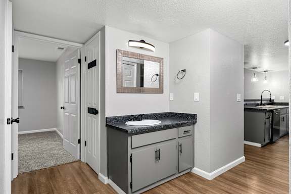 Bathroom vanity with granite countertop and adjacent hallway at Redwood Cove Apartments, Chico