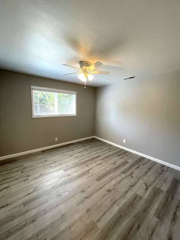 Unfurnished bedroom with wood style flooring and natural light at OSM Properties Homes & Apartments, Chico, California