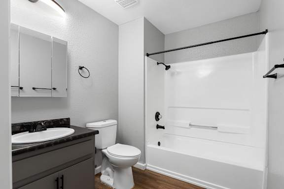 Bathroom with dark vanity and white tub surround at Redwood Cove Apartments, Chico, CA 95928