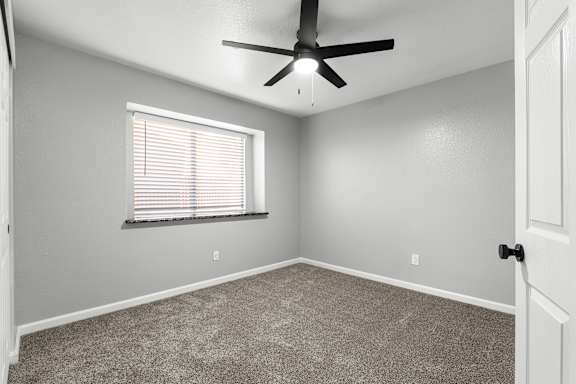 Empty carpeted bedroom with window and ceiling fan at Redwood Cove Apartments, Chico, 95928