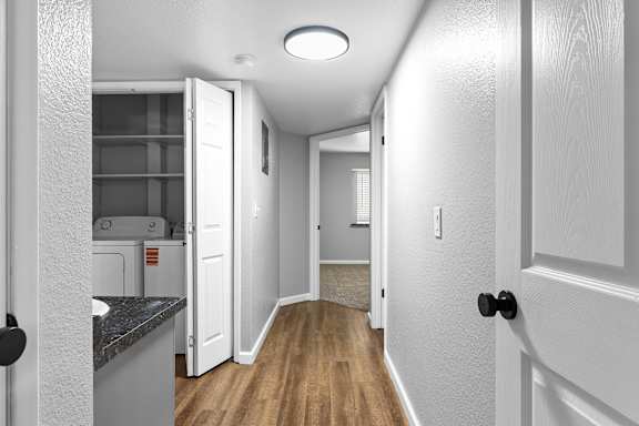 Hallway with laundry closet and wood style flooring at Redwood Cove Apartments, California