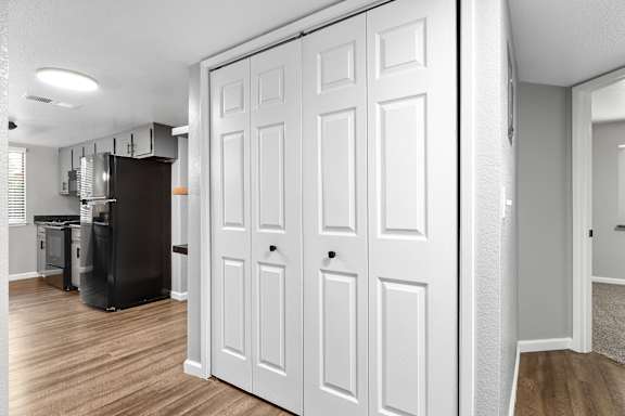Hallway view with bifold closet doors and open kitchen at Redwood Cove Apartments, Chico, CA