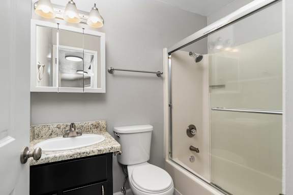 Bathroom with granite vanity and glass shower door at OSM Properties Homes & Apartments, California