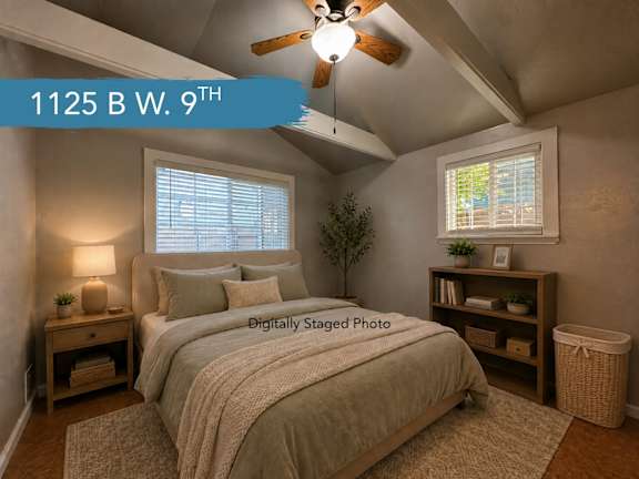 A bedroom with a bed, nightstand, and window.