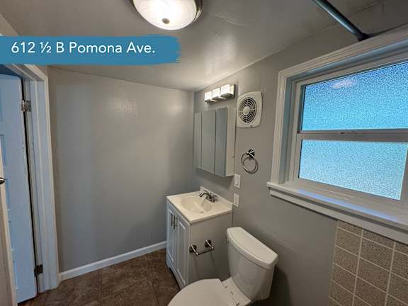 A bathroom with a toilet, sink, and window.