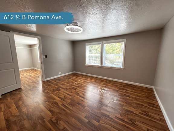 A room with wooden flooring and a window with blinds.