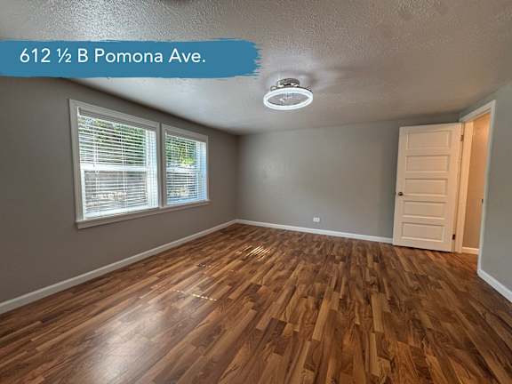 A room with wooden flooring and a window with blinds.