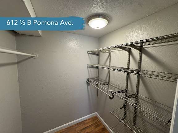 A walk-in closet with shelving and a light on.