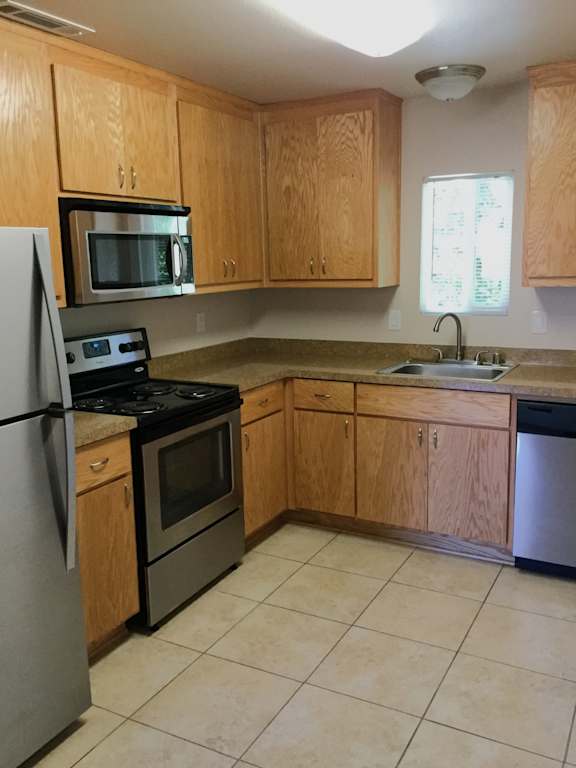Kitchen with oak cabinets and beige tile flooring at OSM Properties Homes & Apartments, Chico, CA