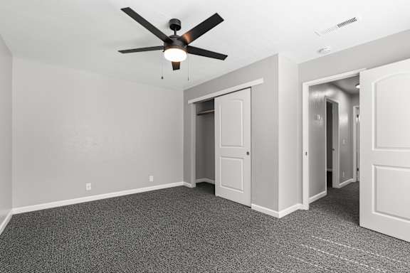 Bedroom with walk-in closet and dark carpet at OSM Properties Homes & Apartments, Chico