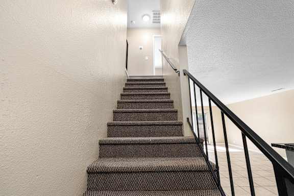 Interior staircase with carpeted steps and metal railing at Cedar Park Apartments, Chico, California