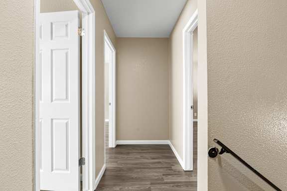 Hallway with wood style flooring and neutral walls at Cedar Park Apartments, Chico