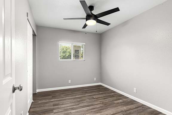 Empty bedroom with wood style floor and window at OSM Properties Homes & Apartments, Chico, CA 95926