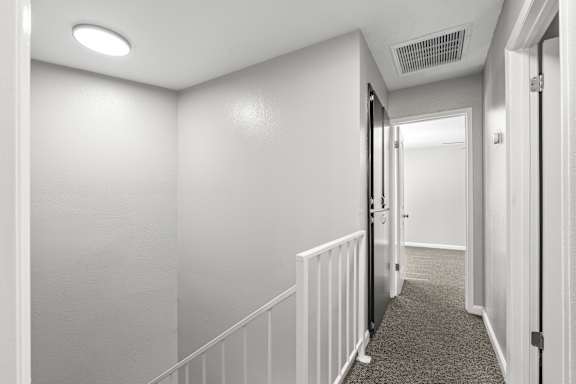 Upstairs hallway with white railing and gray carpet at OSM Properties Homes & Apartments, Chico, CA