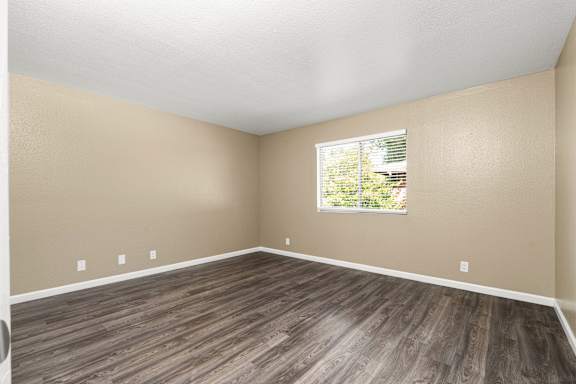 Empty room with laminate flooring and window at Cedar Park Apartments, California
