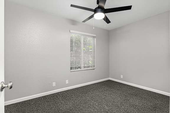 Spacious bedroom with charcoal carpet and window blinds at OSM Properties Homes & Apartments, California