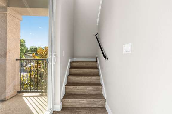 Staircase up to second floor. Vinyl plank flooring on stairs, handrail on right side of stairwell.