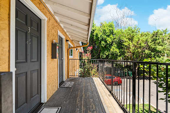 Covered front porch with metal railing and door entry at OSM Properties Homes & Apartments, Chico, California