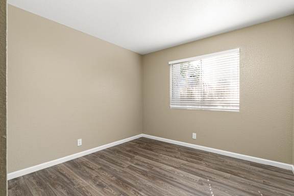 Vacant bedroom with window blinds and baseboards at Cedar Park Apartments, California