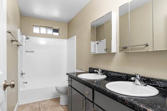 Bathroom with double vanity and black countertop at Cedar Park Apartments, Chico, CA