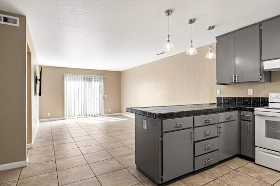 Kitchen island with gray cabinets and black countertop at Cedar Park Apartments, California