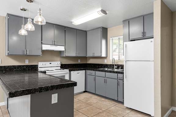 Modern kitchen with gray cabinetry and black countertops at Cedar Park Apartments, California, 95926