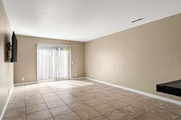 Empty living room with tile flooring and window blinds at Cedar Park Apartments, Chico, CA 95926