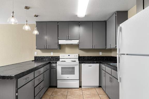 Kitchen with white appliances and dark countertops at Cedar Park Apartments, Chico, CA