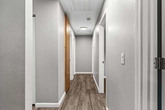 Narrow hallway with wood style flooring and white walls at OSM Properties Homes & Apartments, California