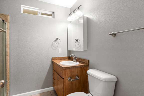 Bathroom with wood vanity and medicine cabinet at OSM Properties Homes & Apartments, Chico, 95926
